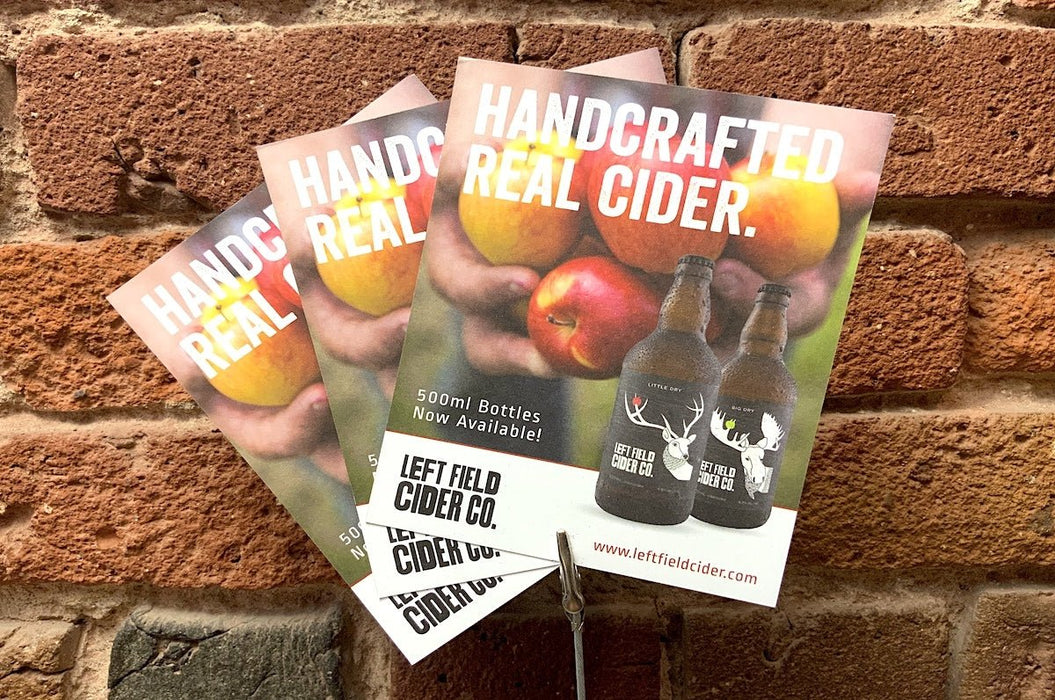 Custom 14pt uncoated matte postcards for Left Field Cider Co featuring Handcrafted Real Cider printed graphic against a brick wall background