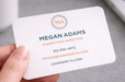 Hand holding a 20pt white cotton letterpress business card with copper foil stamping and rounded corners