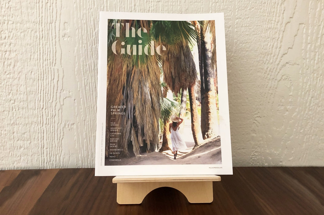 Birch Plywood book display stand holding Palm Springs Life's publication The Guide on a wooden table.