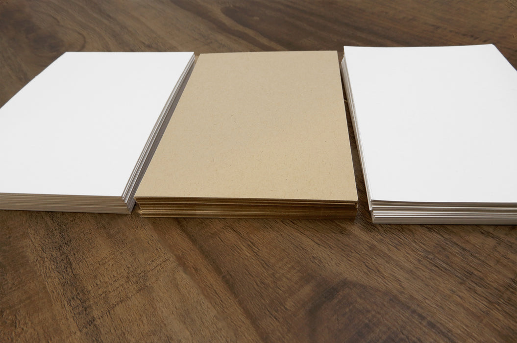 Piles of coated and uncoated white and desert storm uncoated blank card stocks.