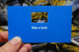 Royal blue business card with a rectangle cut out in the middle with "Take a look." in white below | Clubcard Printing USA