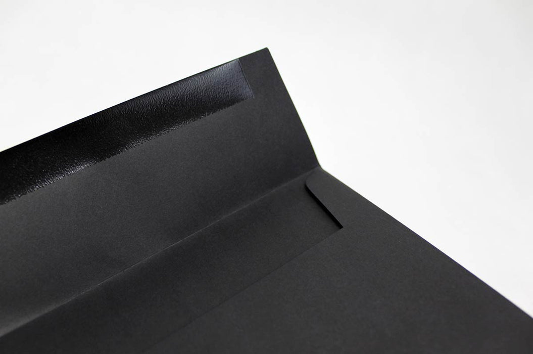 Close up of the front of an uncoated blank eclipse black envelope with the seal flap open on a white background.