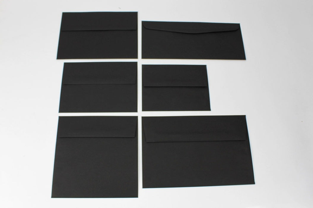Six different sizes of uncoated blank eclipse black envelopes on a white background.