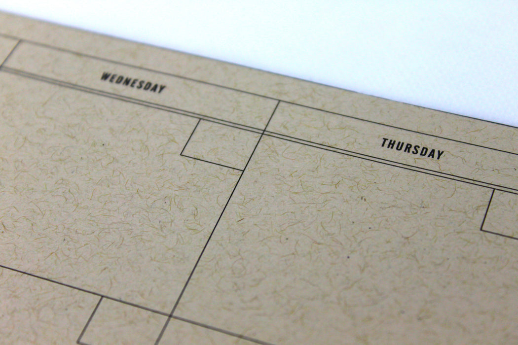 Close up of the weekday line of a natural kraft dateless monthly planner notepad.